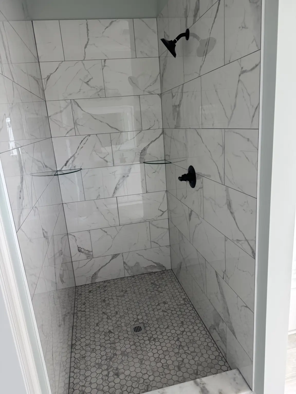 Completed custom tile shower with marble-look tile and mosaic flooring